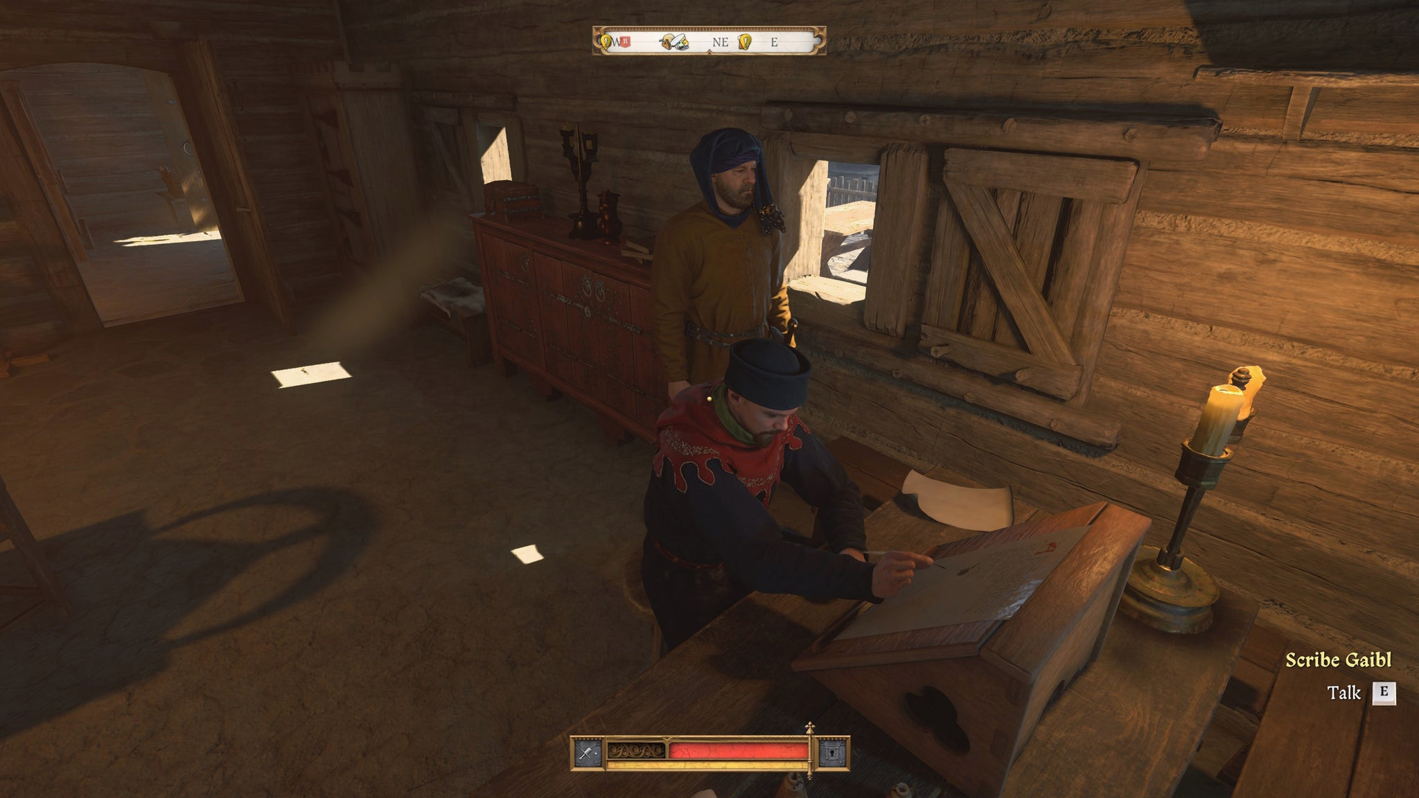Писарь Гайбл в Kingdom Come Deliverance 2 сидит за деревянным столом и занимается своей работой