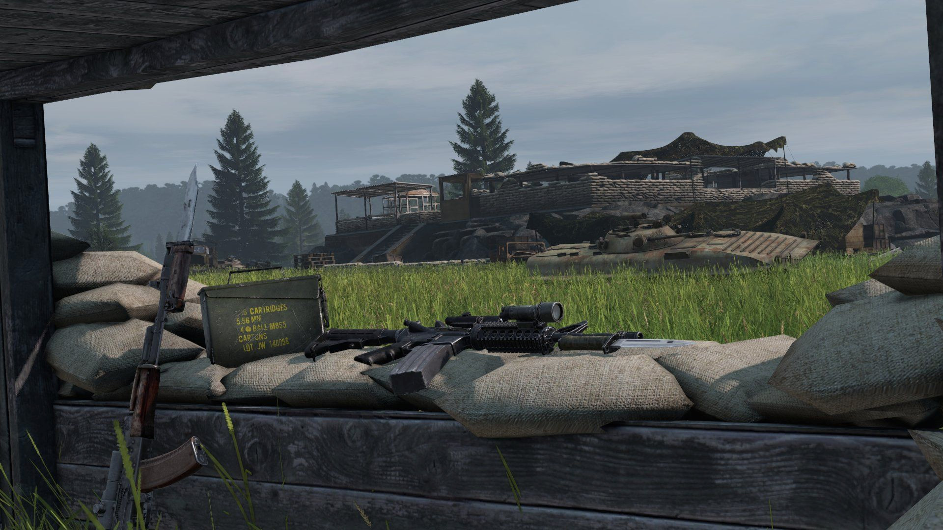 Лучшие серверы DayZ: AK47 и снайперская винтовка лежат на самодельной баррикаде в травяном поле с видом на здание